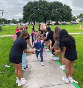 College students giving high-fives to elementary school kids.