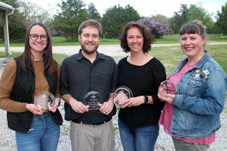 Picture of four individuals holding awards.