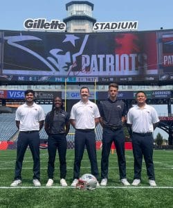 A photo of five athletic trainers on a football field.