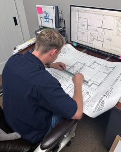 Tyler Call at a desk with drafting paper and a computer.